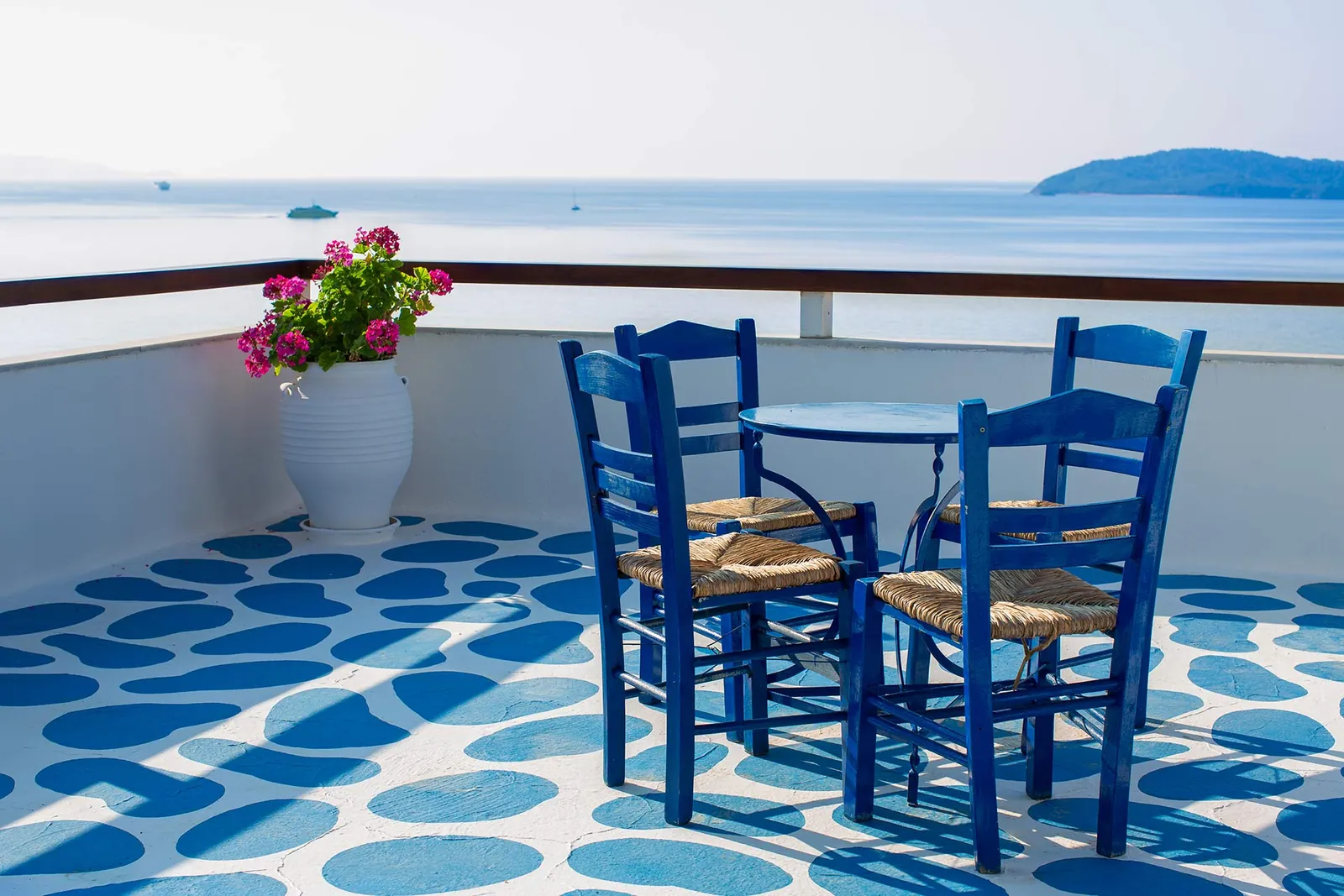 Blue chairs on the pebble-tiled terrace above the sea